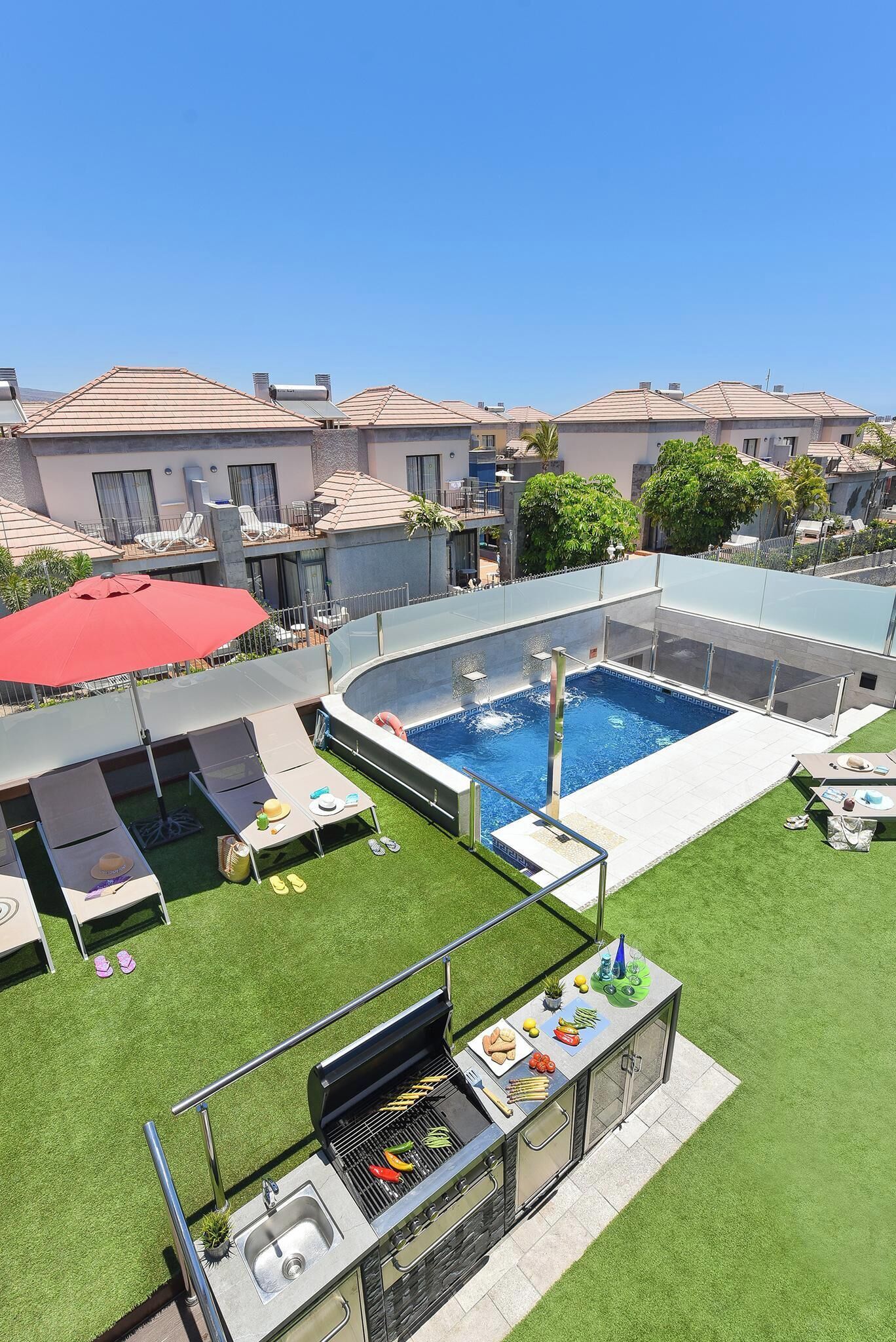 A rooftop pool with a glass enclosure, a barbecue area, and a lounge with sunbeds.