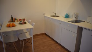A small kitchenette with a white countertop, a sink, and a stove. There are two white chairs and a table with oranges and condiments. - Studio Penthouse La Casa de Manuel, is located in Portomarín, 22km from Sarria. (Portomarín)