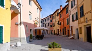 A narrow street with buildings on either side, outdoor seating, and a planter with plants. - Sea 5 Terre,quiet,indipendent,lawn,bbq,FreeWiFi,children,pets (levanto)