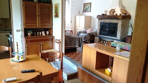 A cozy living room with a fireplace, wooden furniture, and a dining area with a table and chairs. - Sea 5 Terre,quiet,indipendent,lawn,bbq,FreeWiFi,children,pets (levanto)