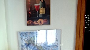 A room with a wooden table displaying various travel maps and brochures, a framed map on the wall, and a poster above. - Sea 5 Terre,quiet,indipendent,lawn,bbq,FreeWiFi,children,pets (levanto)