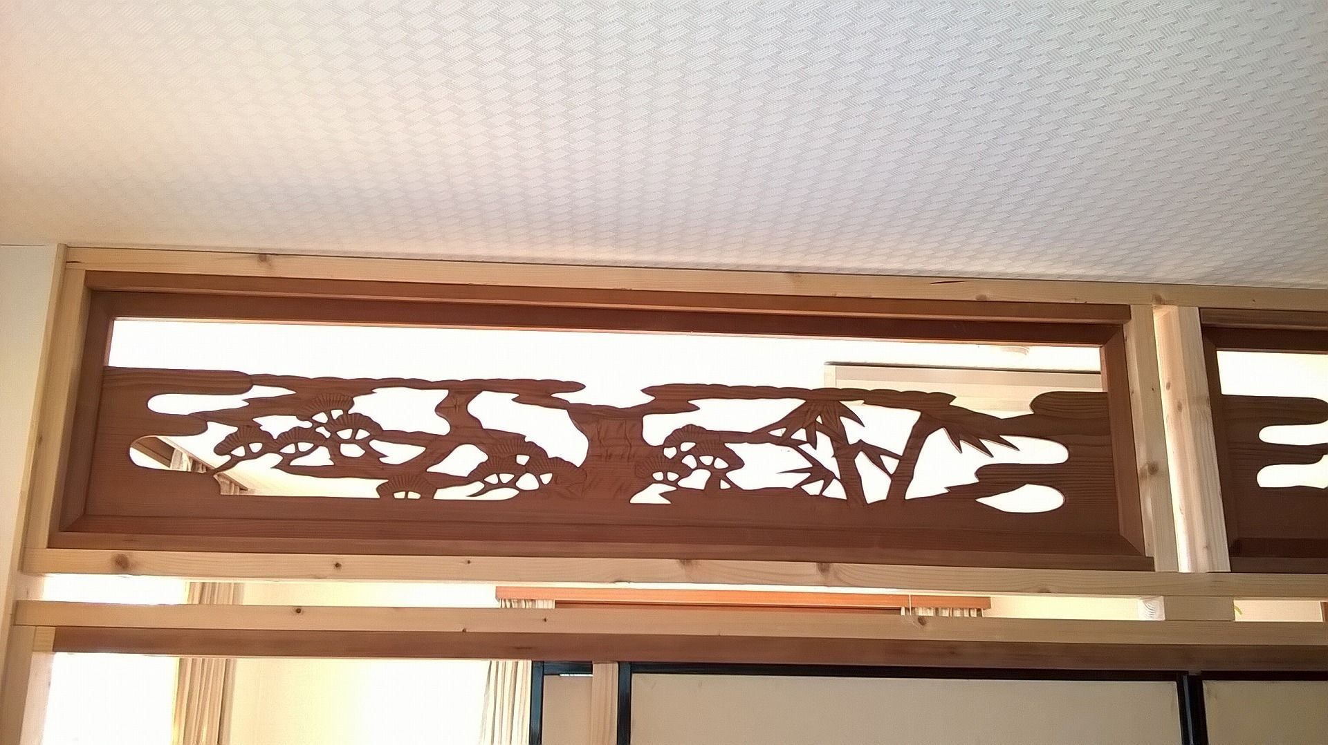 A wooden decorative panel with a cut-out design of trees and foliage.