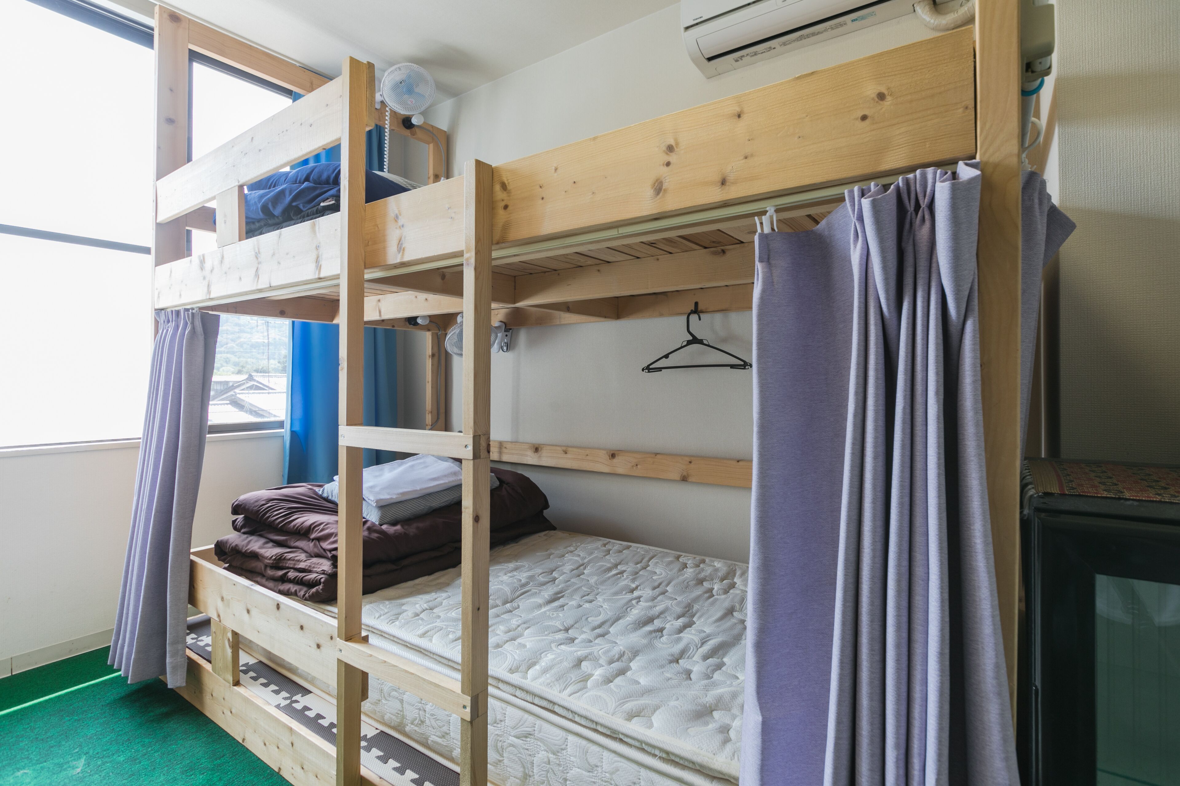 A bunk bed room with a window, a heater, and a television.
