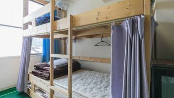 A bunk bed room with a window, a heater, and a television.