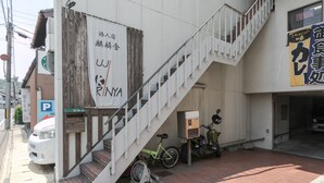 Un immeuble avec un escalier menant à un étage supérieur, un vélo garé à l’extérieur et une enseigne avec des caractères japonais.
