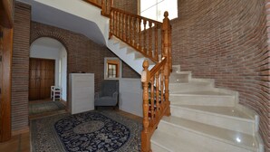 A spacious living area with a wooden staircase, a large rug, and a brick wall. - Villa with stunning panoramic views to the sea, privacy and swimming pool (Mijas)