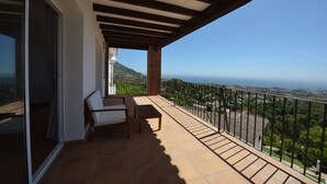 A balcony with a view of the ocean and a mountain, furnished with a chair and a table. - Villa with stunning panoramic views to the sea, privacy and swimming pool (Mijas)