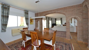 A dining area with a wooden table and chairs, a red patterned rug, and a brick wall. - Villa with stunning panoramic views to the sea, privacy and swimming pool (Mijas)