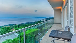 A balcony with a view of a body of water and distant land, a glass railing, and a table with a chair. - Villa Sole - five bedrooms with sea views and a private pool by MyWaycation (Poljane)