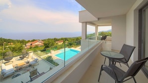 A balcony with a glass railing overlooking a swimming pool and a view of the sea. - Villa Sole - five bedrooms with sea views and a private pool by MyWaycation (Poljane)