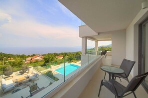 A balcony with a glass railing overlooking a swimming pool and a view of the sea. - Villa Sole - five bedrooms with sea views and a private pool by MyWaycation (Poljane)