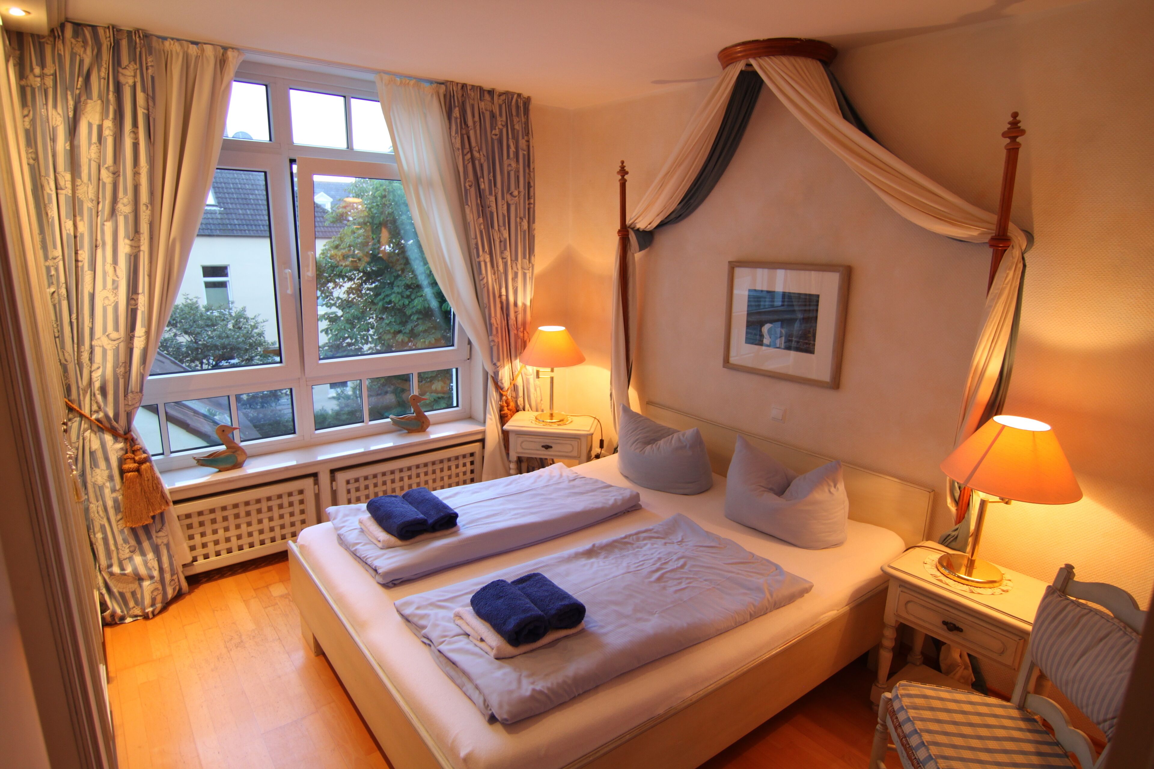 Une chambre avec deux lits, une fenêtre avec des rideaux, une table de chevet avec une lampe et une chaise.