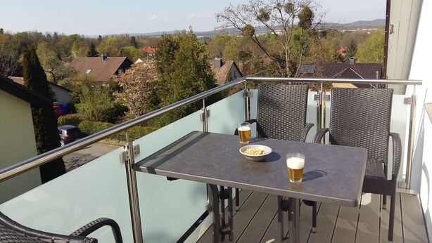 Un balcón con una mesa, dos sillas y dos vasos de cerveza.