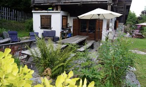 A rustic cabin with a wooden deck, outdoor seating, and a small table.