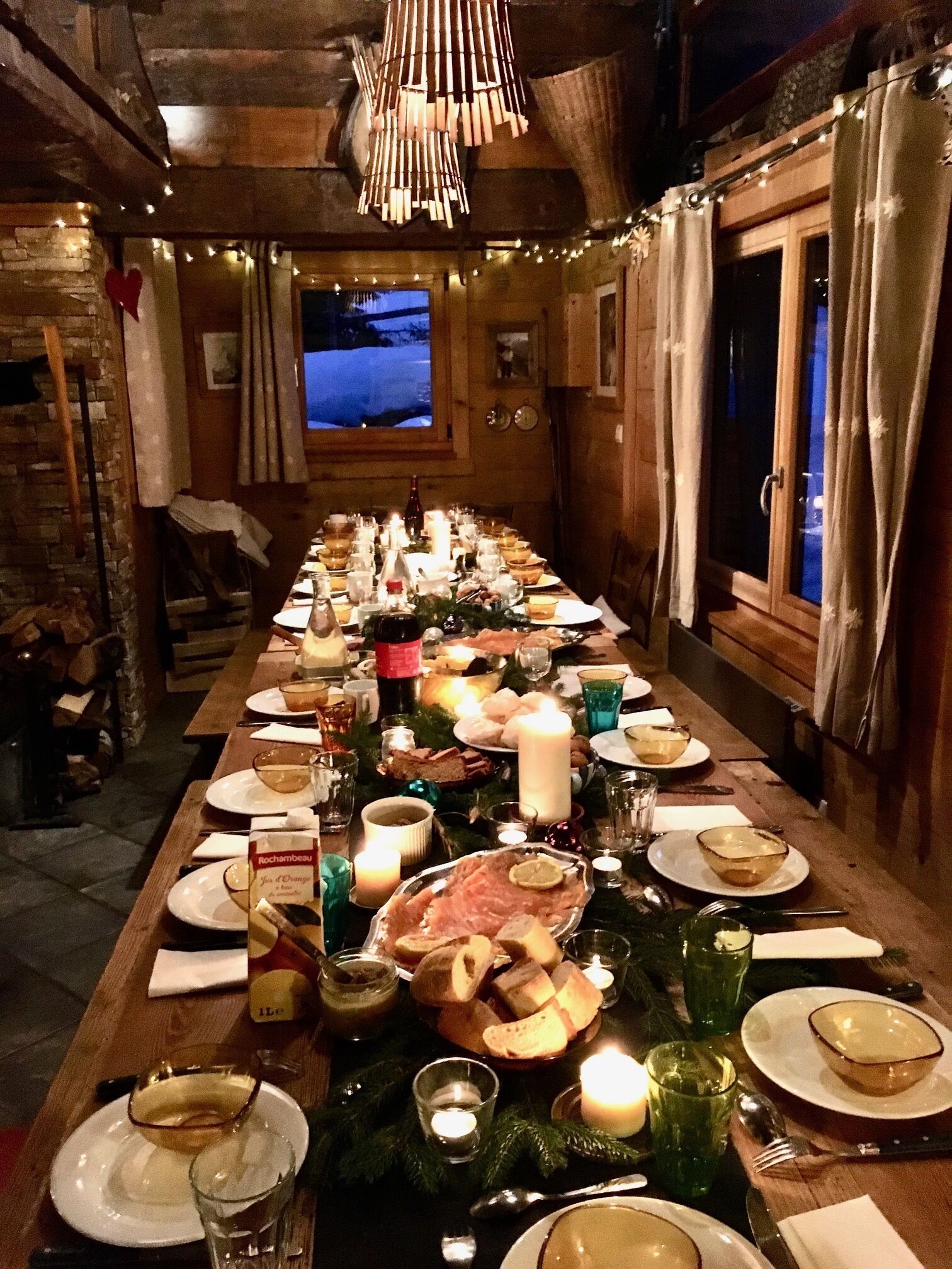 Een lange eettafel gedekt voor een maaltijd, met kaarsen, borden en glazen.