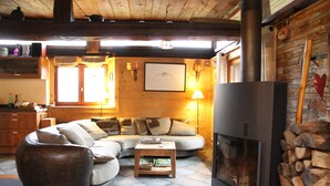 Una sala de estar acogedora con un sofá seccional, una chimenea y una pared de piedra.