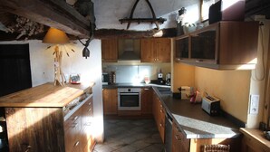 Una cocina con armarios de madera, horno empotrado, lavamanos y encimera.