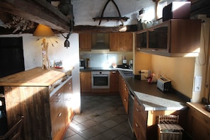 Una cocina con armarios de madera, horno empotrado, lavamanos y encimera.