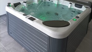 A rectangular hot tub with a built-in heater, a control panel, and a water pump.