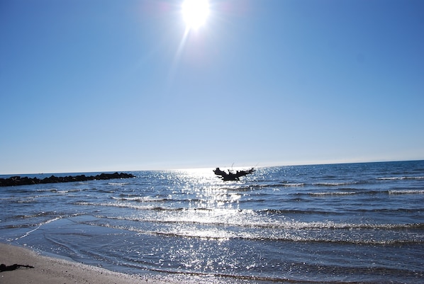 A beach with calm waves and a clear sky.