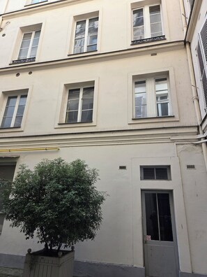 A building with multiple windows, a door, and a small tree in a planter.