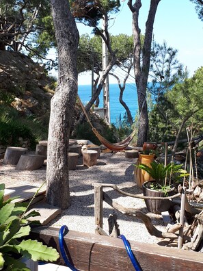 Relax in a serene hammock amidst lush greenery and a distant ocean view.