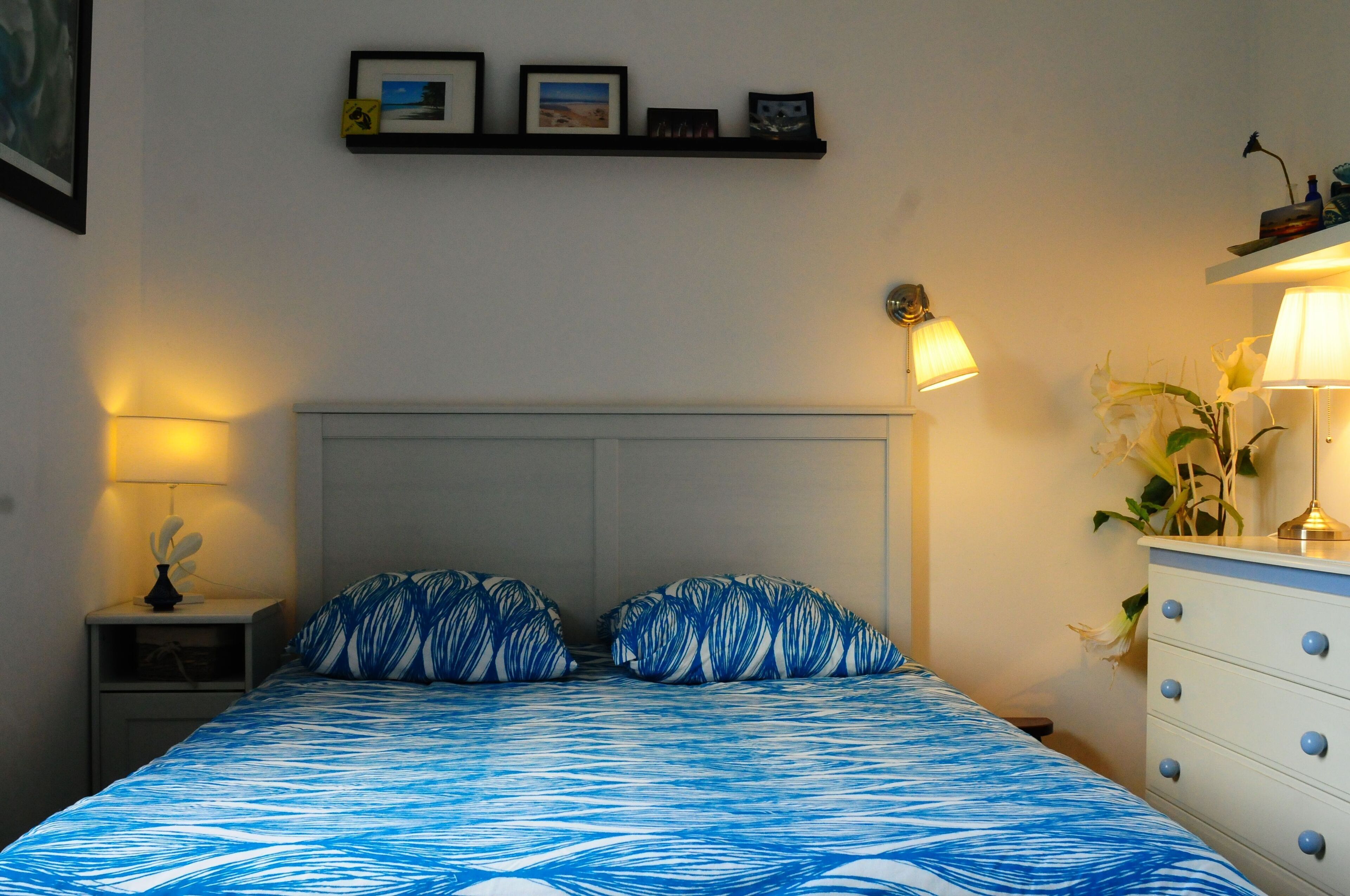 Ein Schlafzimmer mit einem Bett, Nachttischen, einem Schminktisch und Wandlampen.