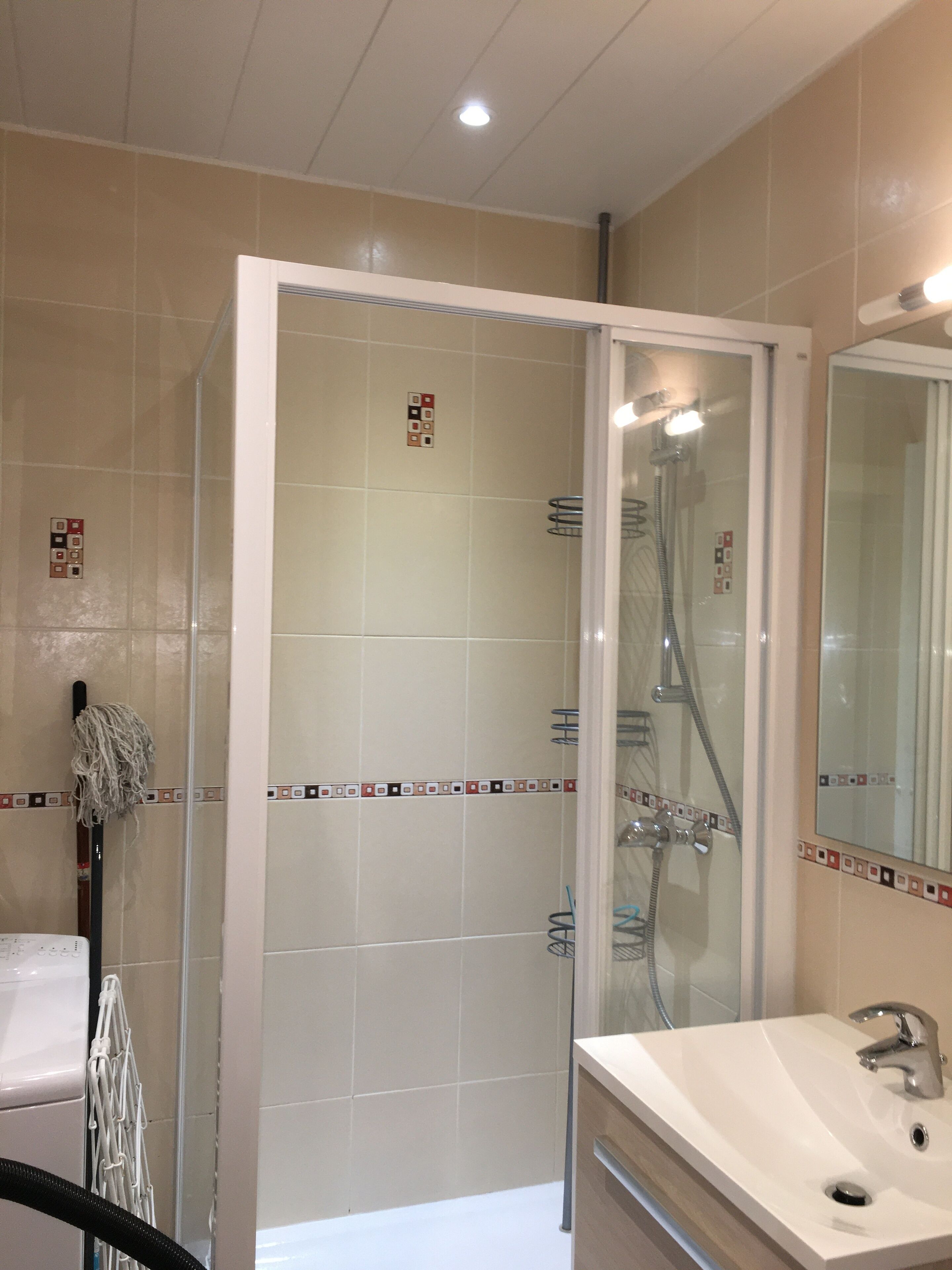 Een moderne badkamer met een glazen douchecabine, een wit wastafelmeubel en een spiegel.