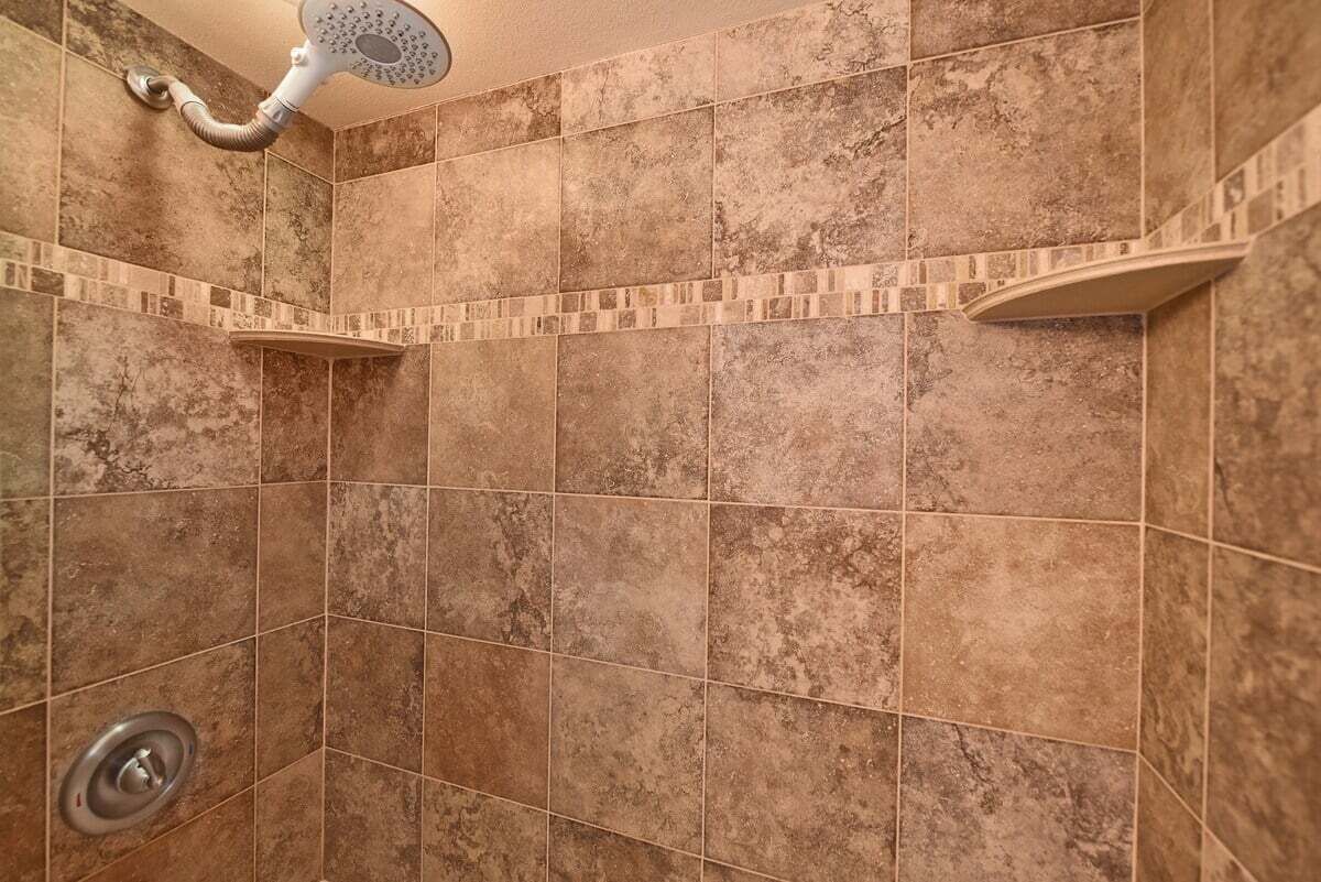 A shower area with tiled walls and a showerhead.