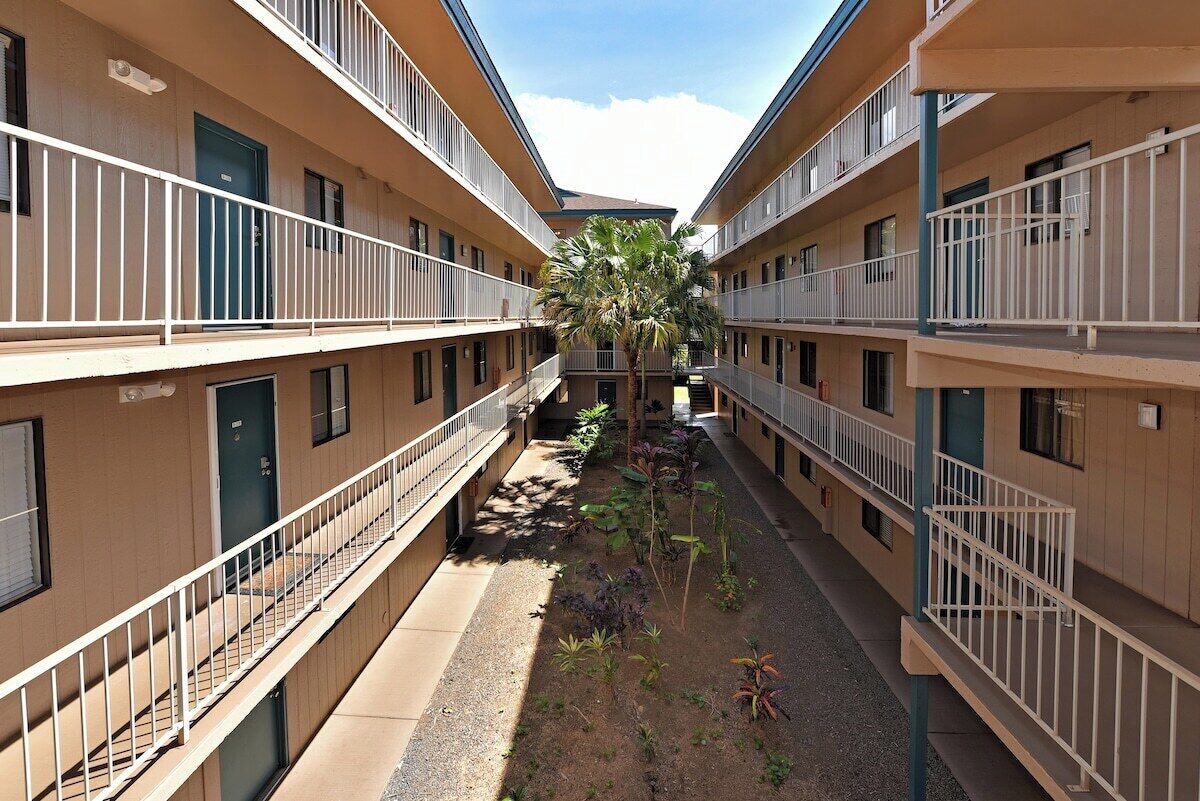 A multi-story hotel with balconies and a central courtyard with plants.