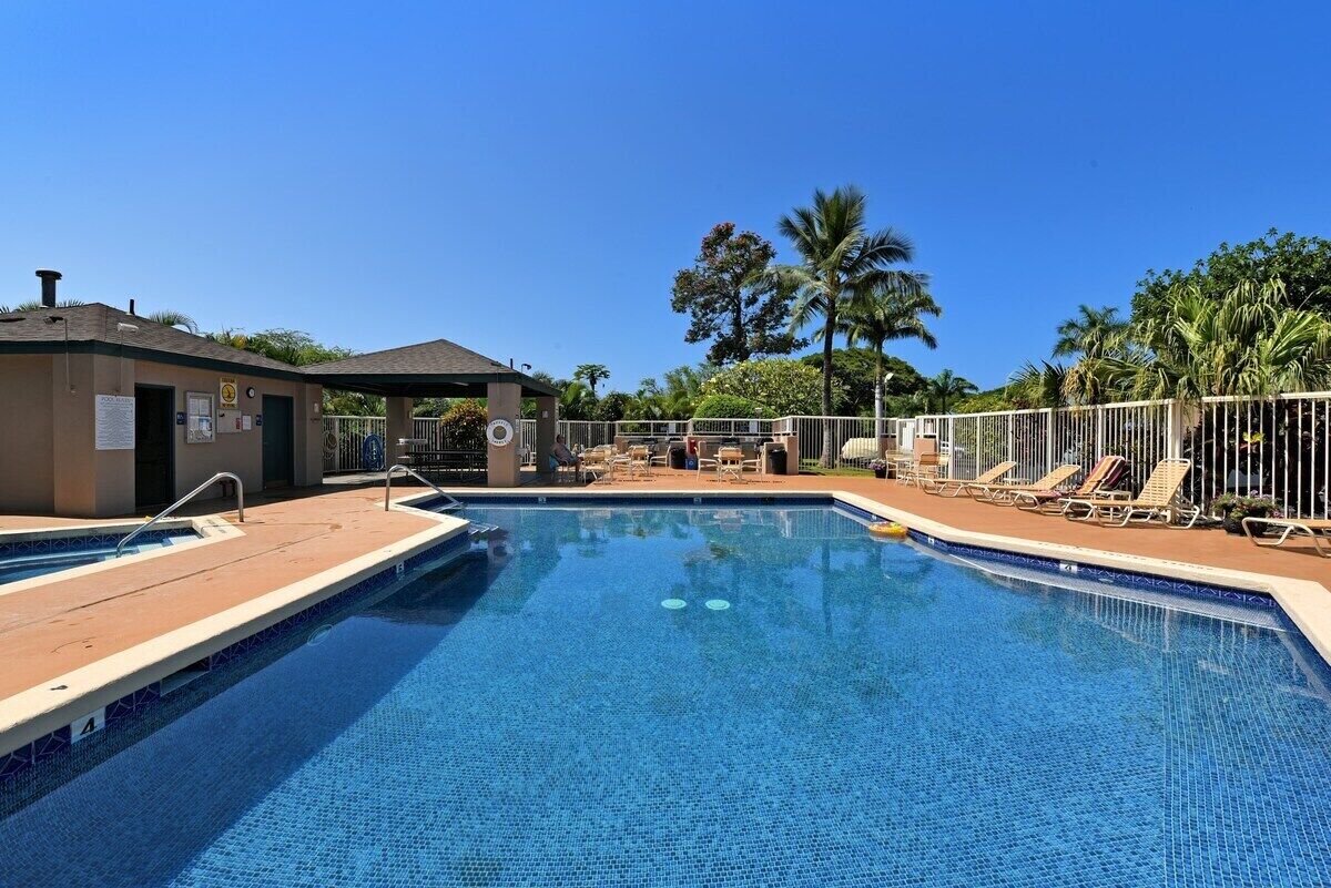 A swimming pool with lounge chairs and a covered area.