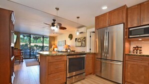 A modern kitchen with wooden cabinets, stainless steel appliances, and a large island. - Family Getaway 3BD Across from  Beach-Pacific Shores B102 (Kihei)