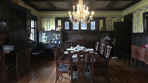 Une salle à manger avec une grande table en bois, un plafond décoré et un lustre.
