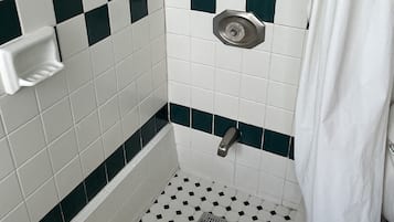 A shower area with checkered tile walls, a showerhead, and a drain.