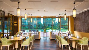 A restaurant with multiple tables and chairs, large windows with a view of greenery, and hanging light fixtures. - Minyoun Langzhong Ancient City Resort (Nanchong)