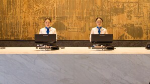 A reception desk with two employees, a patterned wall, and hanging lights. - Minyoun Langzhong Ancient City Resort (Nanchong)