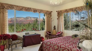 Un dormitorio con una ventana grande, una cama, un escritorio y una silla.
