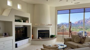 Una sala de estar moderna con chimenea, un ventanal con vista a la montaña y una zona de estar acogedora.