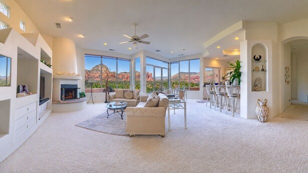 A spacious living room with a fireplace, large windows, and a view of red rock formations.