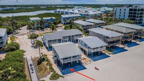 A coastal hotel with multiple-story buildings, a parking area, and a beach view.