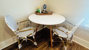A corner dining area with a round table and two wicker chairs with checkered cushions. - Studio Near the Plantations (Charleston)