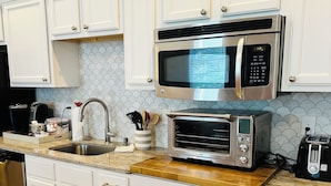 A kitchen with white cabinets, a stainless steel microwave, a toaster, and a wooden countertop. - Studio Near the Plantations (Charleston)