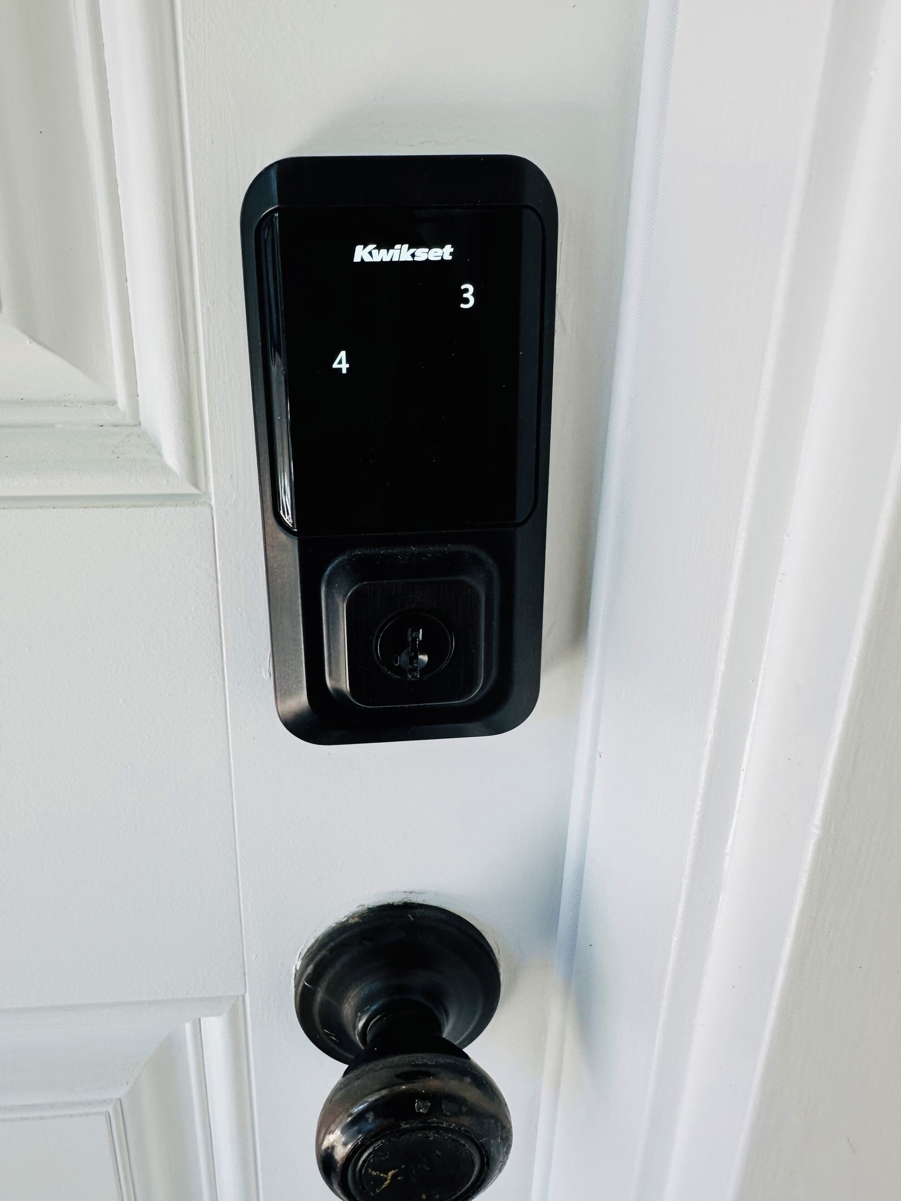 Una cerradura Kwikset en una puerta blanca.