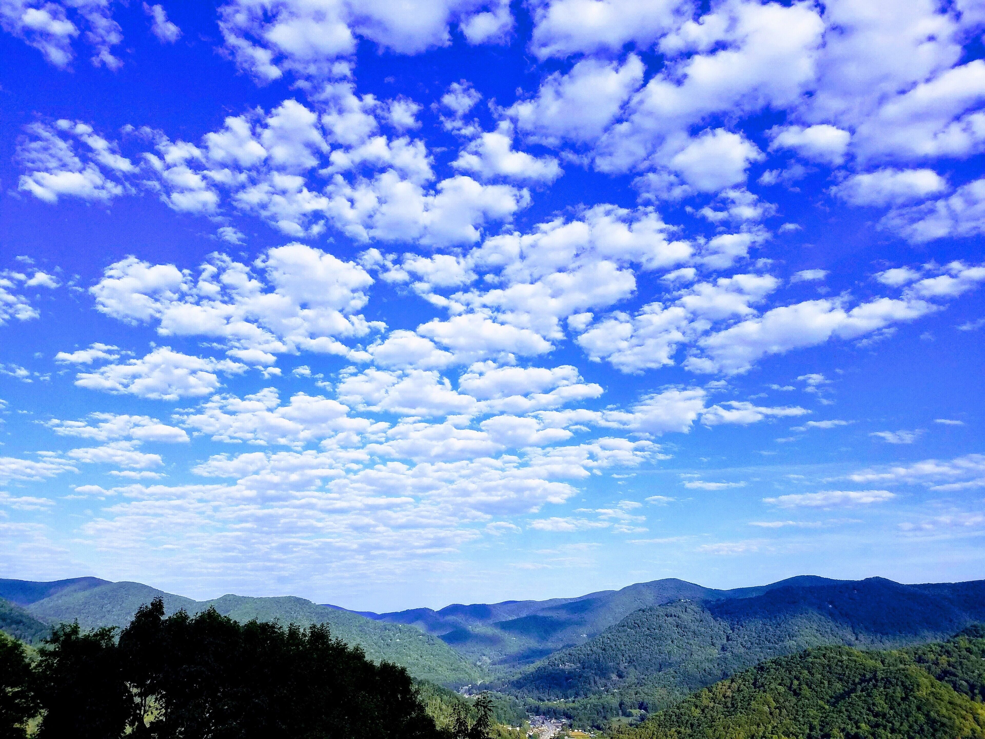 A mountainous landscape with a clear sky and scattered clouds.