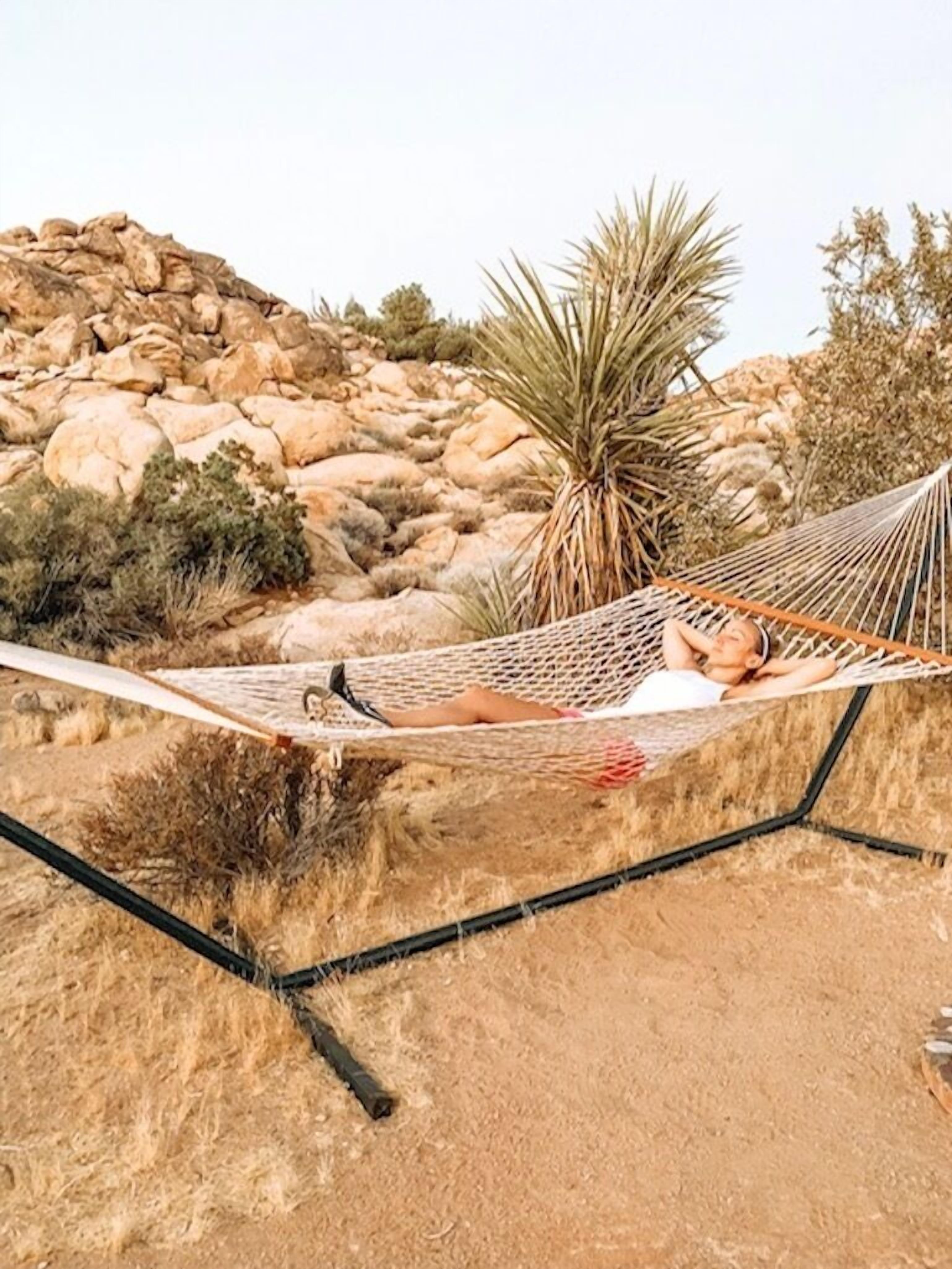 A hammock set up in a rocky outdoor area with sparse vegetation.