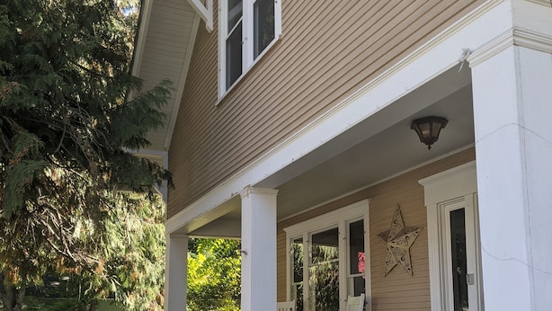 A two-story house with a porch, white railings, and a small garden area. - Walking distance everywhere, yard, front porch and hot tub! (Coeur d'Alene)