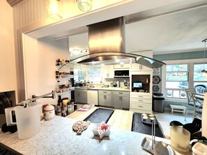 A modern kitchen with a curved island, stainless steel appliances, and a view of the outdoors.