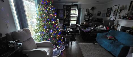 Una sala de estar con piso de madera, un árbol de Navidad, un sofá y un perro.