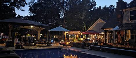 Un área de piscina al aire libre con sombrillas, asientos y un pabellón.