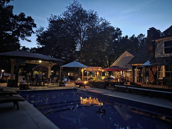 An outdoor pool area with umbrellas, seating, and a gazebo.
